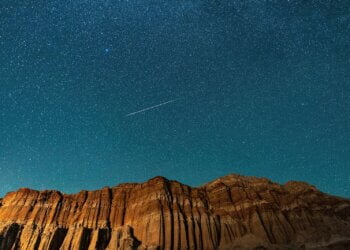 a night sky with a plane flying over a mountain