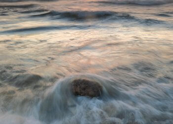 A sunset over the ocean with rocks in the foreground